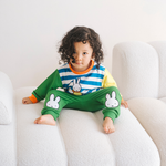 Kind dat de nijntje on the Move-bamboe-loungeset draagt, bestaande uit een fiets-sweatshirt en een groene joggingbroek