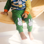 Kind dat de nijntje on the Move-bamboe-loungeset draagt, bestaande uit een fiets-sweatshirt en een groene joggingbroek