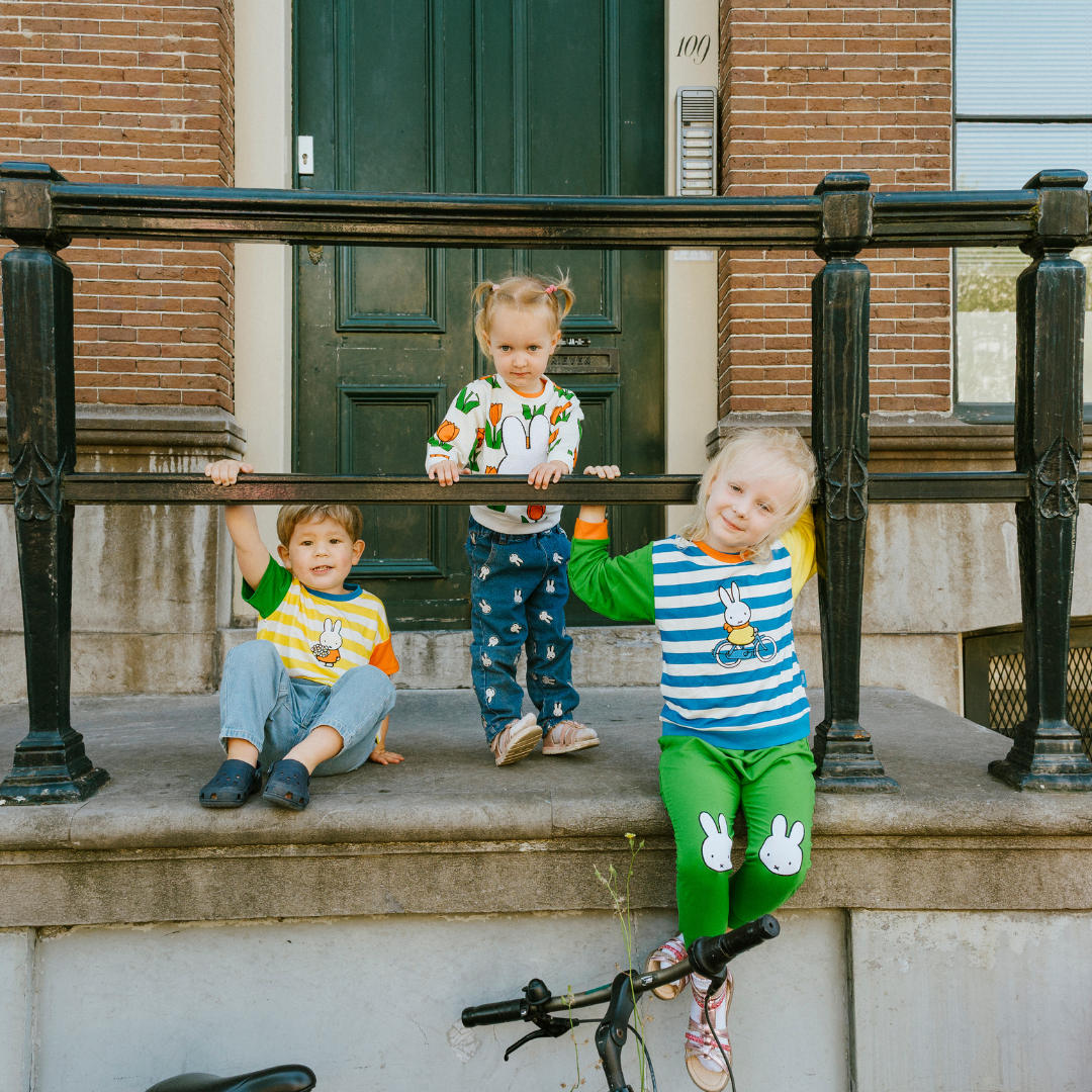 Kind dat de nijntje on the Move-bamboe-loungeset draagt, bestaande uit een fiets-sweatshirt en een groene joggingbroek